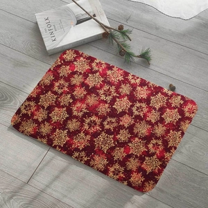 Macro detail of red Christmas floor mat with gold snowflake pattern on grey wood floor