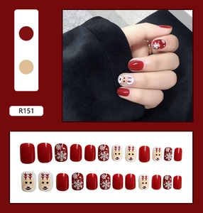 Detail of red Christmas press-on nails with reindeer and snowflake patterns