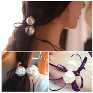 Close-up of black ribbon hair scrunchie with two large white pearls worn on hair and wrist