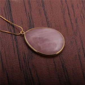 Elegant gold-tone teardrop pendant necklace featuring a polished pink gemstone inlay