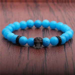 Macro view of blue frosted agate beads and black skull charm on an elastic bracelet