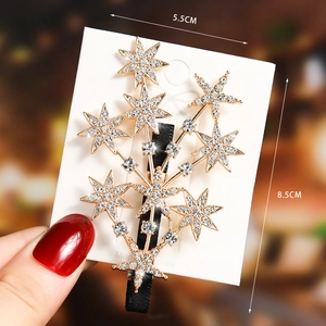 Close-up of golden star-shaped hair clip with inlaid rhinestones and duckbill grip