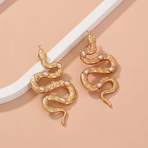 Vintage matte gold snake earrings with inlaid pearls on a modern minimalist background