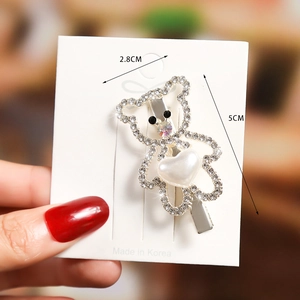 Detail of bear hair clip with sparkling rhinestones and a heart pearl on white card