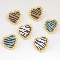 Detailed view of heart-shaped earrings with zebra pattern and gold beaded edges