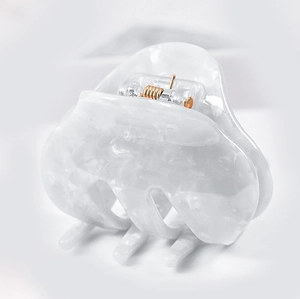 Close-up of white marble acetate hair claw clip with golden metal spring mechanism