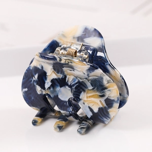 Detail of large acetate hair claw clip with blue and yellow marble pattern and metal spring