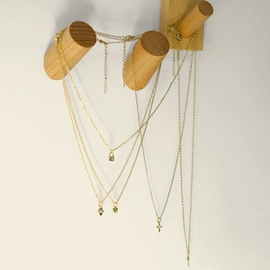 Detail showing gold pendant necklaces with lock, heart and cross on wooden hangers