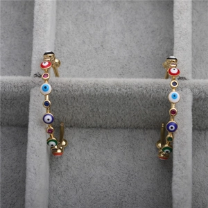 Detailed close-up of gold evil eye heart earrings with colorful zircons on velvet tray