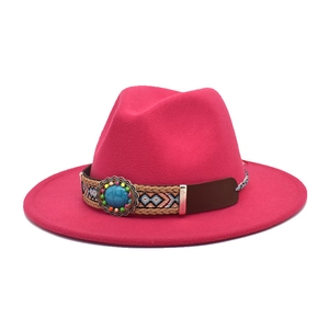 Dettaglio di un cappello fedora rosso rosa con fascia etnica e decoro in gemma turchese