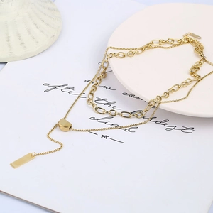 Detail of layered gold titanium steel necklace with rectangular pendant on ceramic plate