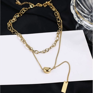 Detailed close-up of double-layered gold titanium necklace with bean pendant on silk
