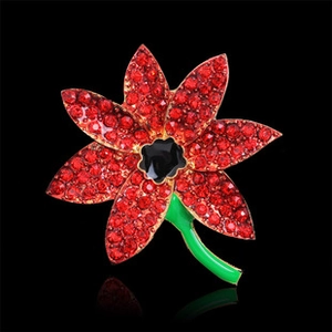Detail shot of a crystal flower brooch with red rhinestones and green enamel stem