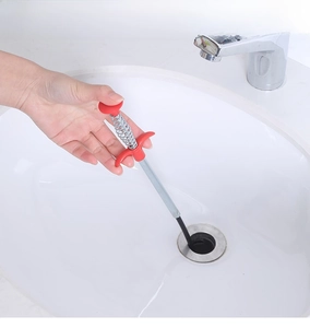 Manual spring drain claw tool clearing hair from a white ceramic bathroom sink