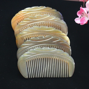 Close-up of five handcrafted yak horn combs with natural textures on black velvet cloth