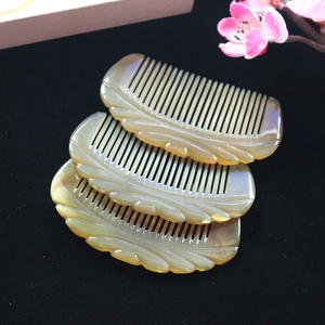 Close-up of three half-moon yak horn combs with leaf carvings on black velvet