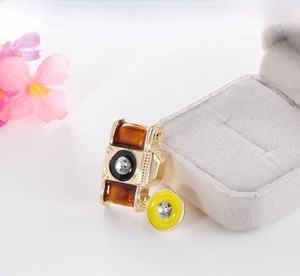 Close-up of vintage camera brooch in gold alloy with amber enamel and zircon details