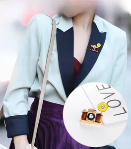 Detail of vintage camera brooch with amber texture and crystal on a blazer lapel