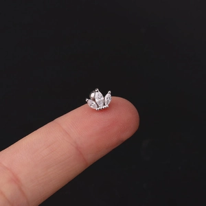 Macro shot of a tiny crown-shaped cartilage stud with marquise cubic zirconia on a fingertip