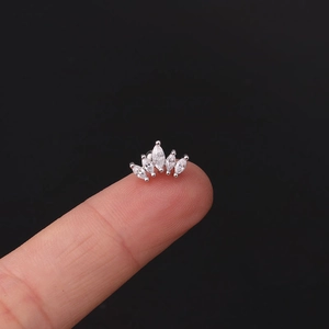 Macro shot of crown cartilage stud with five marquise cubic zirconia on a fingertip