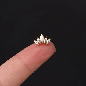 Golden crown ear stud with marquise-cut opal stones shown on fingertip for scale