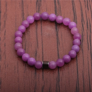 Close-up of purple beaded mood bracelet with dark brown stone cylinder on leather texture