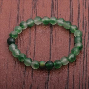 Detail view of multi-tone green stone beads bracelet on a dark textured wooden background