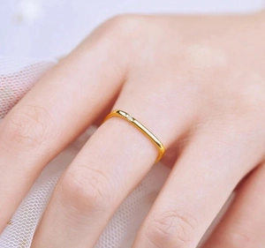 Close-up of a minimalist gold-plated square titanium ring with a small diamond inlay