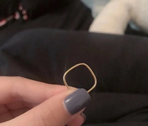 Minimalist square golden titanium steel ring held in hand with a simple thin band design