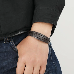 Brown multi-layer braided leather bracelet for men worn with casual outfit on white background