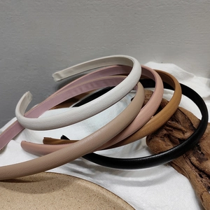 Detail of slim leather headbands in five colors with textured finish on wood block