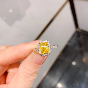 Detailed close-up of emerald-cut yellow gemstone ring with halo diamond setting