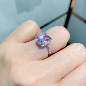 Close-up of a pink rectangle halo ring with sparkling diamonds on a finger