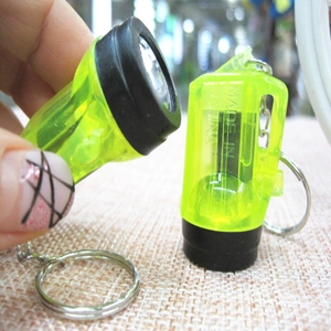 Close-up of a mini neon yellow LED flashlight keychain held in hand for scale and detail