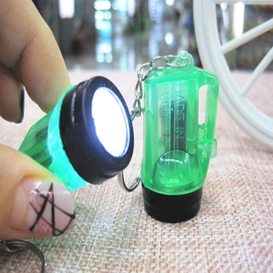 Glow effect of mini green LED flashlight keychain shown held in hand as a portable tool