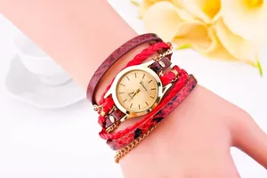 Detail of bohemian wrap watch featuring red braided rope, leopard print band, and gold dial