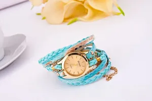 Detail view of turquoise woven wrap strap and golden quartz dial on women fashion watch