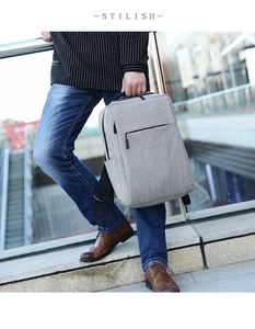 Side view of gray waterproof laptop backpack held by hand against urban background
