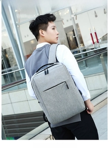 Outdoor view of a grey minimalist laptop backpack with USB port and side water bottle pocket