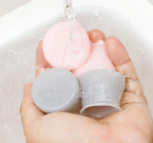 Waterproof silicone furniture leg protectors in pink and gray shown being rinsed under water