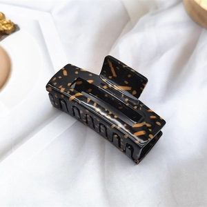 Macro shot of rectangular acetate hair claw clip with amber tortoise shell pattern and gloss