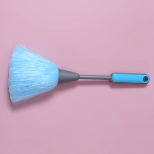 Close-up of blue cleaning duster with gray non-slip handle on pink background