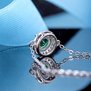 Emerald pendant necklace in 925 silver with sparkling crystals on a dark reflective surface