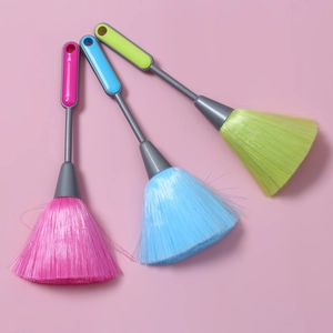Set of pink, blue, and green anti-static computer keyboard duster brushes on a pink background