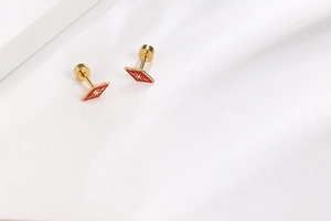 Detail of gold titanium steel diamond studs with red enamel and star pattern