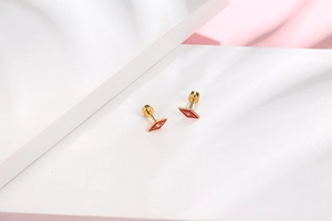 Detail view of red diamond shaped stud earrings with gold starburst pattern on stone