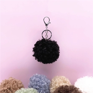 Macro detail of cute curly faux fur pom-pom keychain with silver clasp in various colors