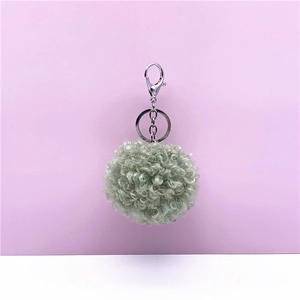 Detailed view of a soft curly plush pom-pom keychain featuring a silver lobster clasp