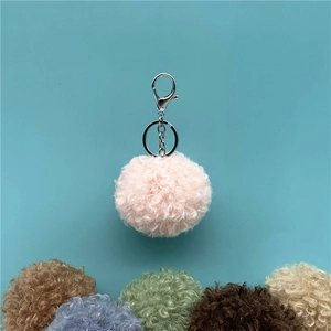 Close-up of a soft pink curly fur pom-pom keychain with silver metal lobster clasp