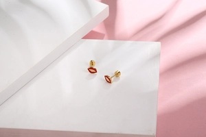 Detail view of mini red lip titanium steel stud earrings with gold plating and screw back